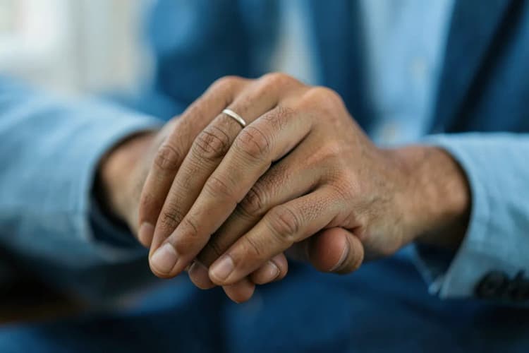 Um profissional de saúde ouvindo atentamente um paciente, com foco nas mãos que se apoiam.
