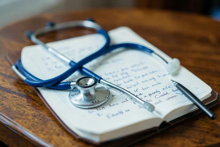 Um estetoscópio e um caderno aberto com anotações sobre uma mesa, simbolizando colaboração.