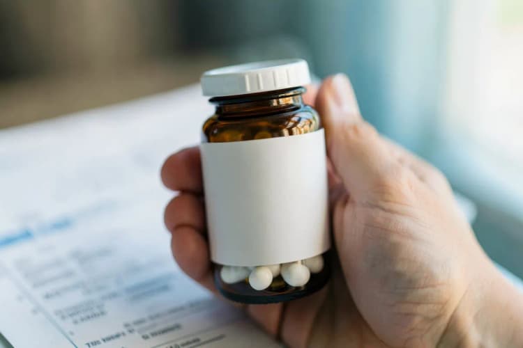 Uma mão segurando um frasco de comprimidos com uma receita médica ao lado, simbolizando a escolha do tratamento.