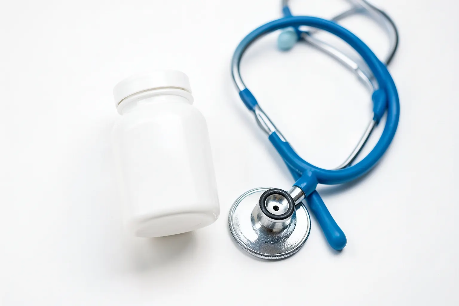 Um frasco de comprimidos com um estetoscópio sobre um fundo branco, simbolizando a medicação psiquiátrica.