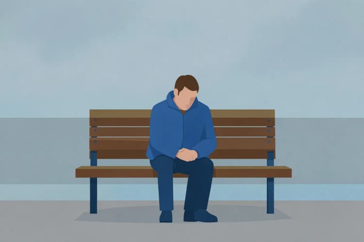 homem com expressão triste sentado em um banco de parque